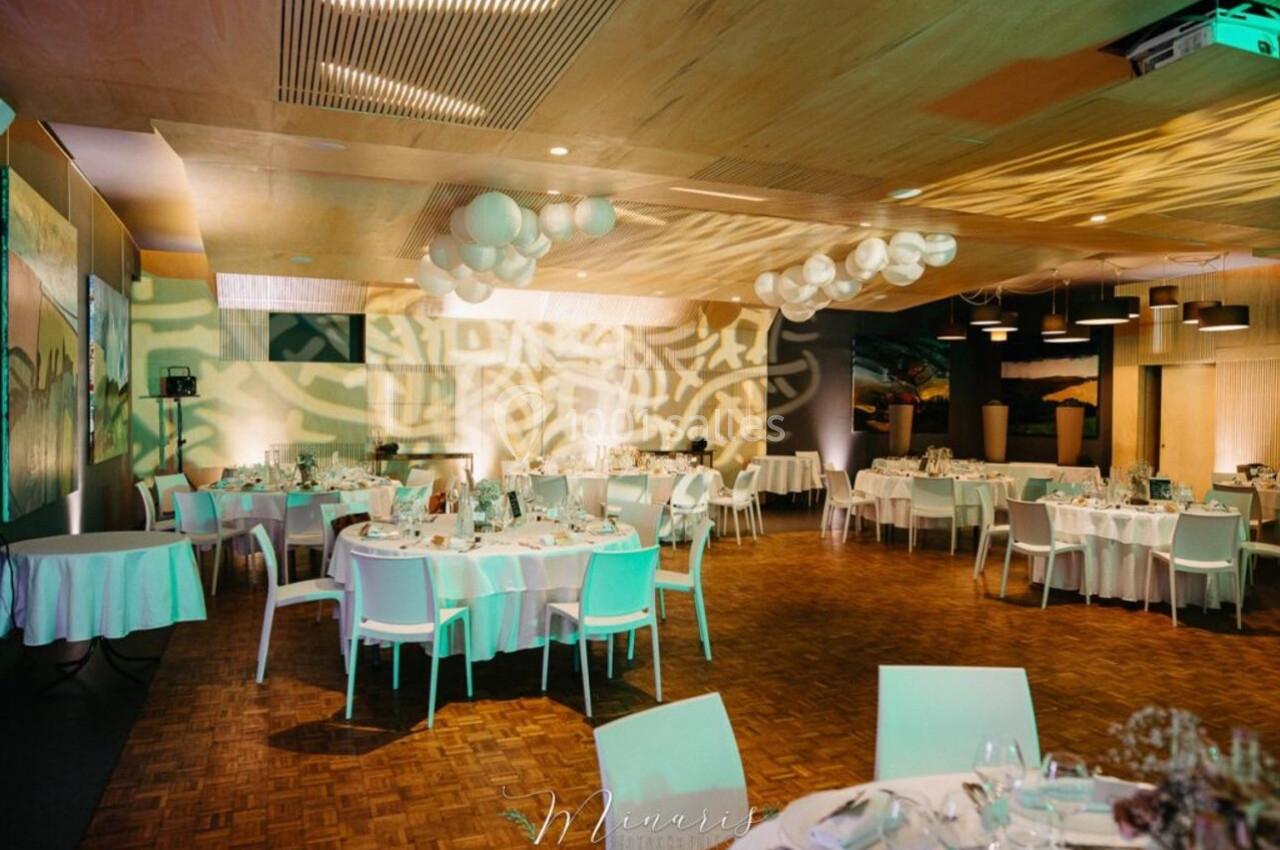 Salle de réception décorée avec des tables rondes dressées, éclairage tamisé et motifs lumineux projetés au mur.