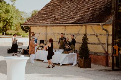 Un chef cuisine sur un barbecue rond dans un jardin aménagé avec des tables et des plantes.