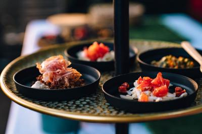 Un chef cuisine sur un barbecue rond dans un jardin aménagé avec des tables et des plantes.