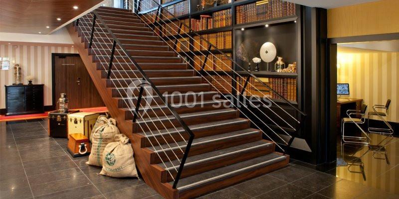 Escalier en bois avec rampe métallique, entouré d'étagères remplies de livres dans un intérieur élégant.