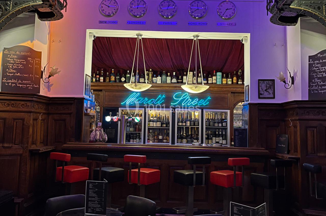 Bar avec comptoir éclairé, tabourets rouges et noirs, enseigne lumineuse ’Maroth Street’ et décor mural rétro.