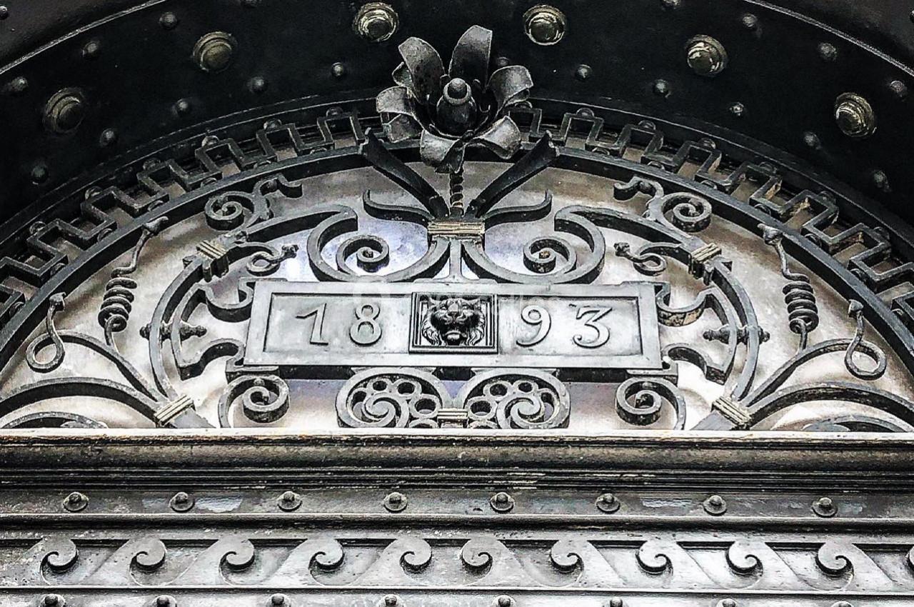 Détail architectural en métal orné de motifs floraux et gravé de la date ’1893’.