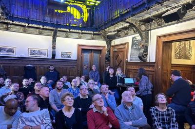 Groupe de personnes discutant dans un espace intérieur éclairé par des lumières vertes, ambiance conviviale.