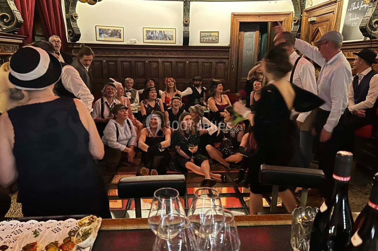 Groupe de personnes en tenue rétro réunies dans une salle élégante, avec des boissons et des décorations festives.