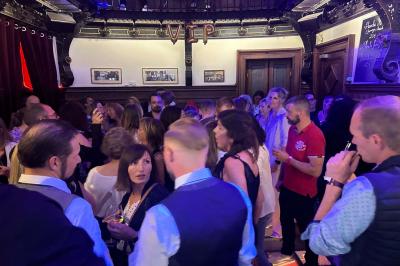 Groupe de personnes discutant dans un espace intérieur éclairé par des lumières vertes, ambiance conviviale.