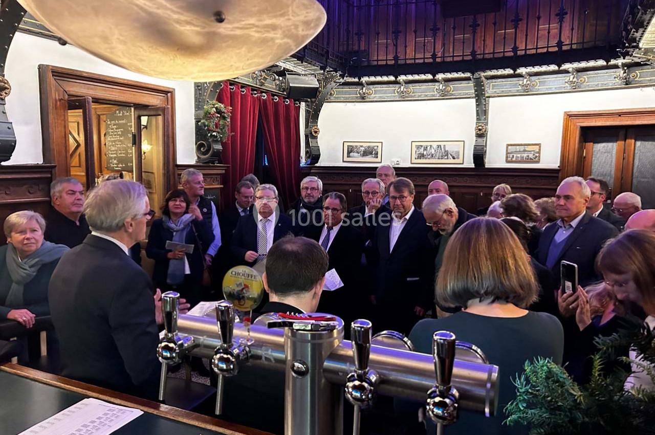 Un groupe de personnes rassemblées dans un bar ou une salle avec un comptoir et une décoration intérieure classique.