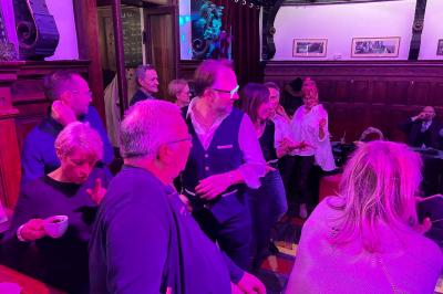 Groupe de personnes discutant dans un espace intérieur éclairé par des lumières vertes, ambiance conviviale.
