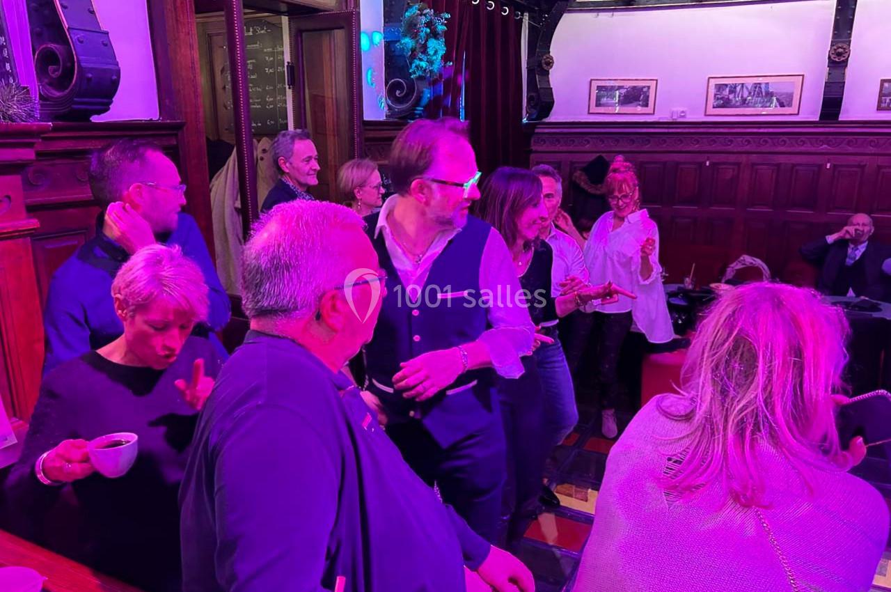 Groupe de personnes discutant et partageant un moment convivial dans un intérieur à l'éclairage coloré.
