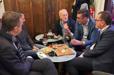 Groupe de personnes discutant dans un espace intérieur éclairé par des lumières vertes, ambiance conviviale.