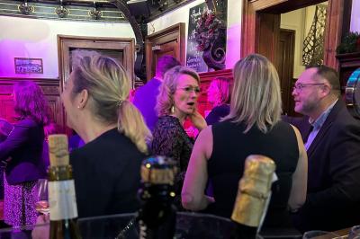 Groupe de personnes discutant dans un espace intérieur éclairé par des lumières vertes, ambiance conviviale.