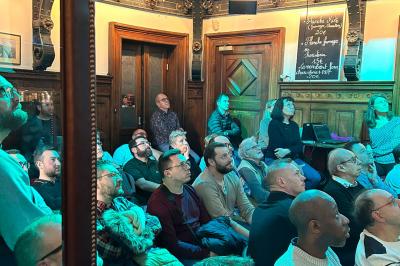 Groupe de personnes discutant dans un espace intérieur éclairé par des lumières vertes, ambiance conviviale.