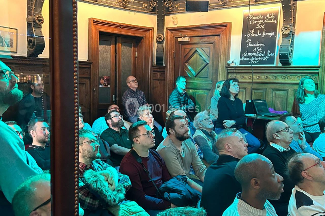 Des personnes assises et debout dans une salle en bois, attentives à une présentation ou un événement.