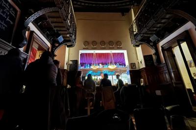Groupe de personnes discutant dans un espace intérieur éclairé par des lumières vertes, ambiance conviviale.