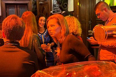 Groupe de personnes discutant dans un espace intérieur éclairé par des lumières vertes, ambiance conviviale.