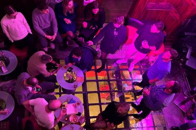Groupe de personnes discutant dans un espace intérieur éclairé par des lumières vertes, ambiance conviviale.