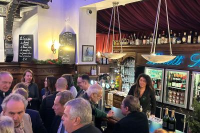 Groupe de personnes discutant dans un espace intérieur éclairé par des lumières vertes, ambiance conviviale.