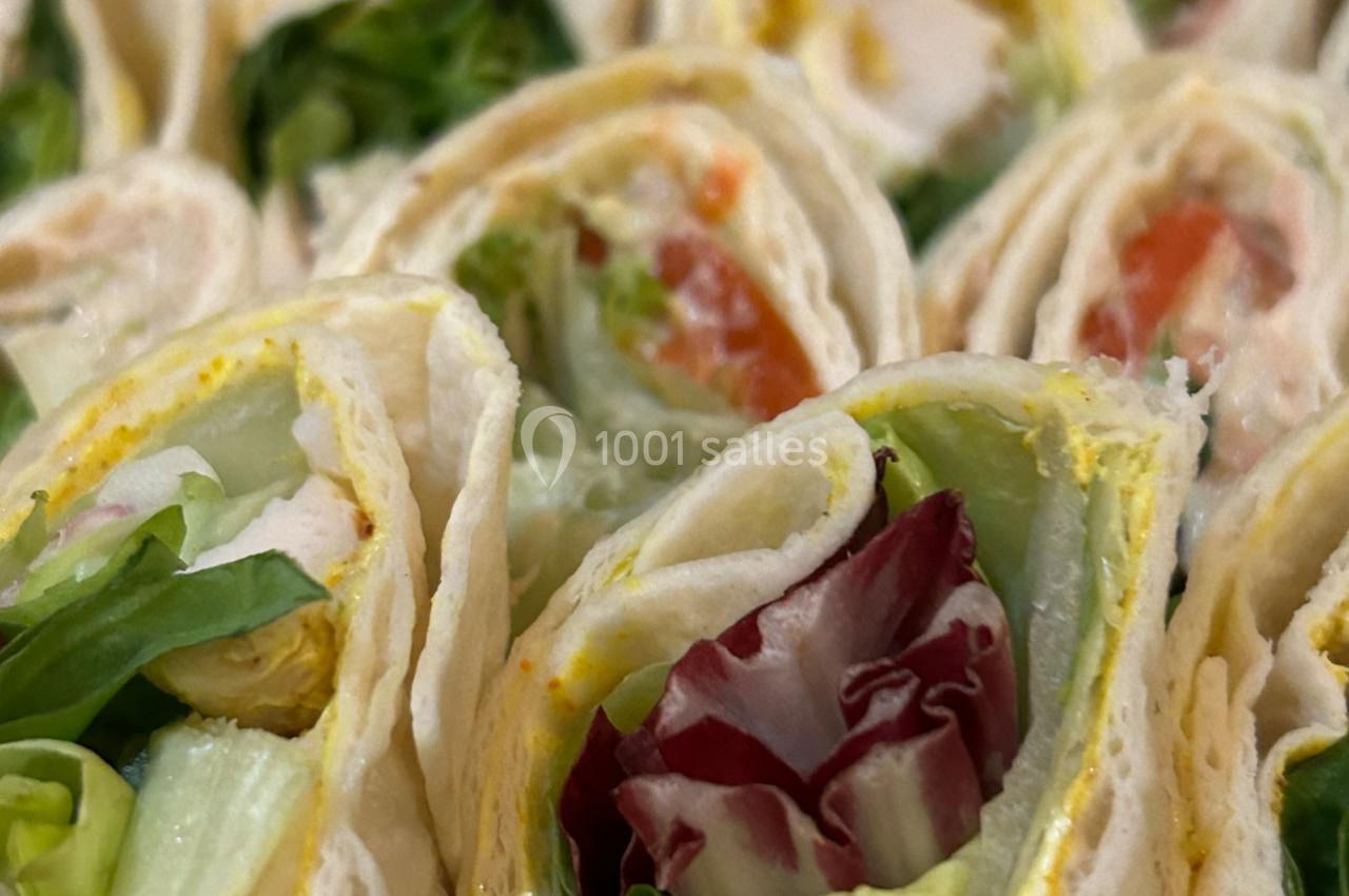 Wraps garnis de salade, tomates, et poulet, présentés en tranches serrées les unes contre les autres.