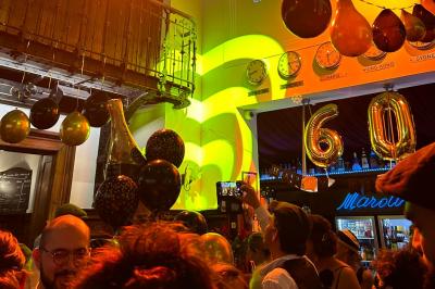 Groupe de personnes discutant dans un espace intérieur éclairé par des lumières vertes, ambiance conviviale.