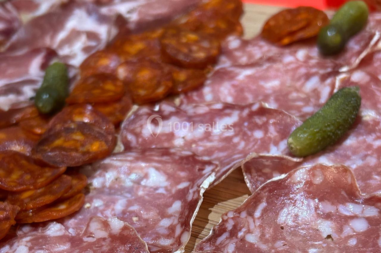 Assortiment de charcuterie avec tranches de saucisson, chorizo et cornichons sur une planche en bois.
