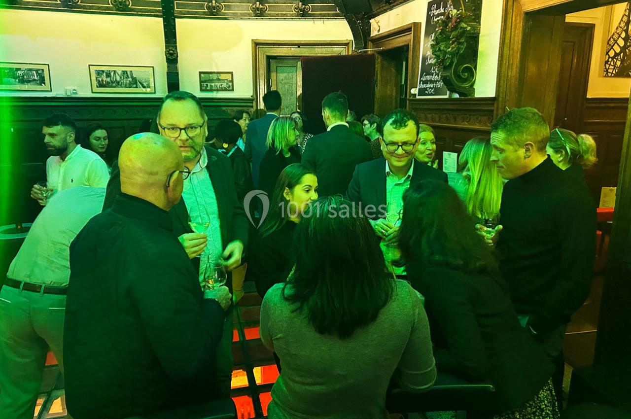 Groupe de personnes discutant dans un espace intérieur éclairé par des lumières vertes, ambiance conviviale.