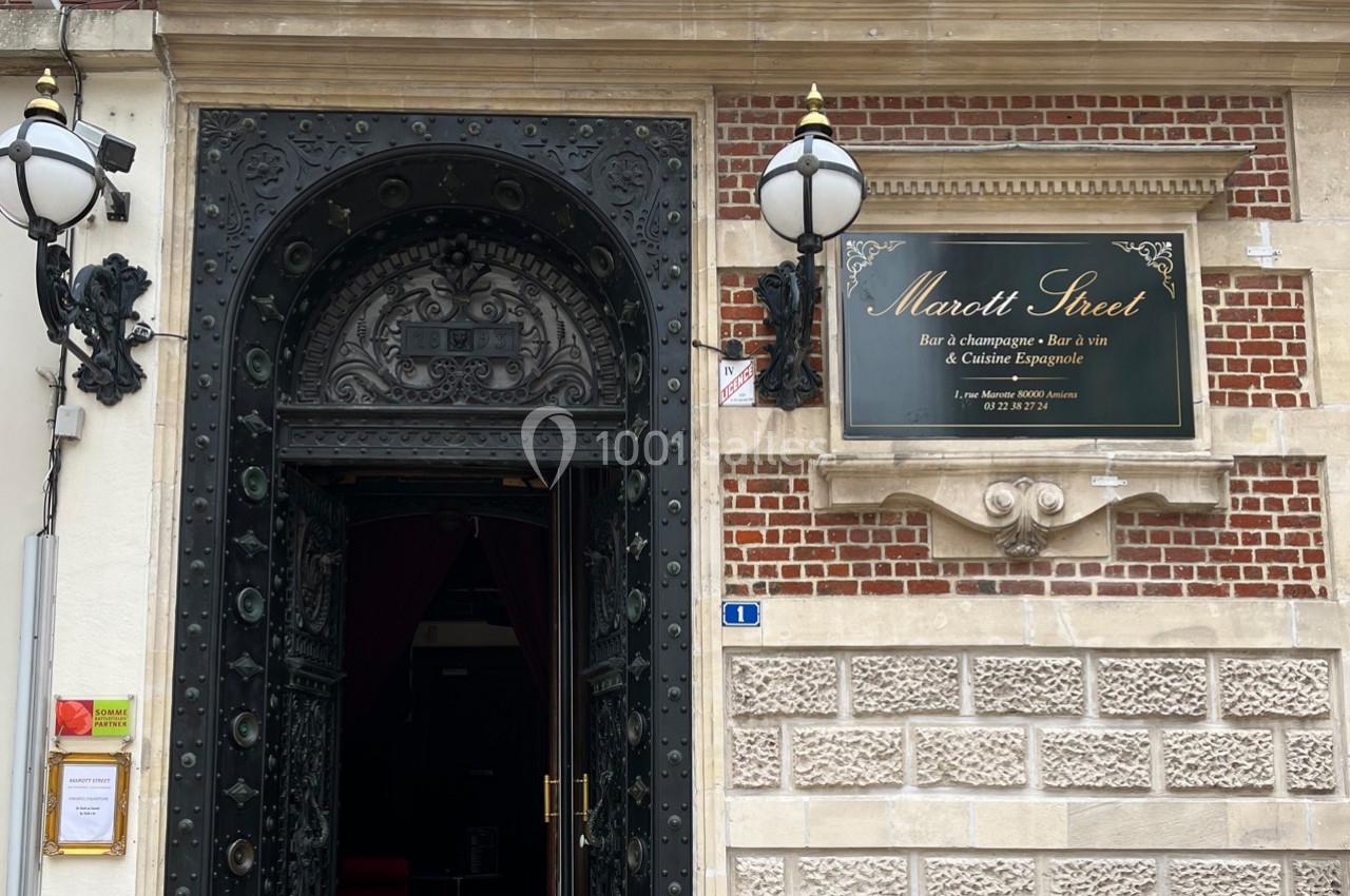 Entrée d'un bar à champagne et à vin avec une porte ornée et une plaque indiquant ’Marott Street’.
