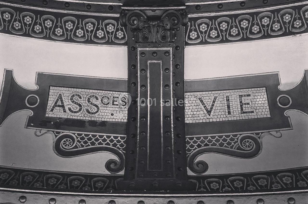Décor en mosaïque avec les mots ’ASSURANCE VIE’ sur une arche métallique ornée de motifs détaillés.
