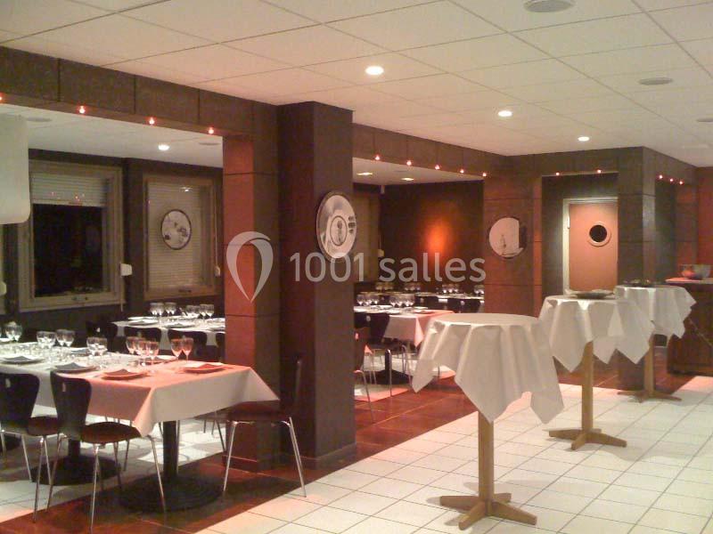 Salle de restaurant avec tables dressées, nappes blanches et éclairage tamisé, prête pour accueillir des convives.