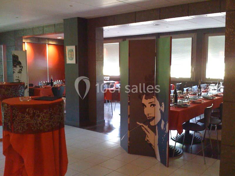 Salle de restaurant avec tables dressées, nappes rouges et cloisons décorées d'illustrations de visage féminin.