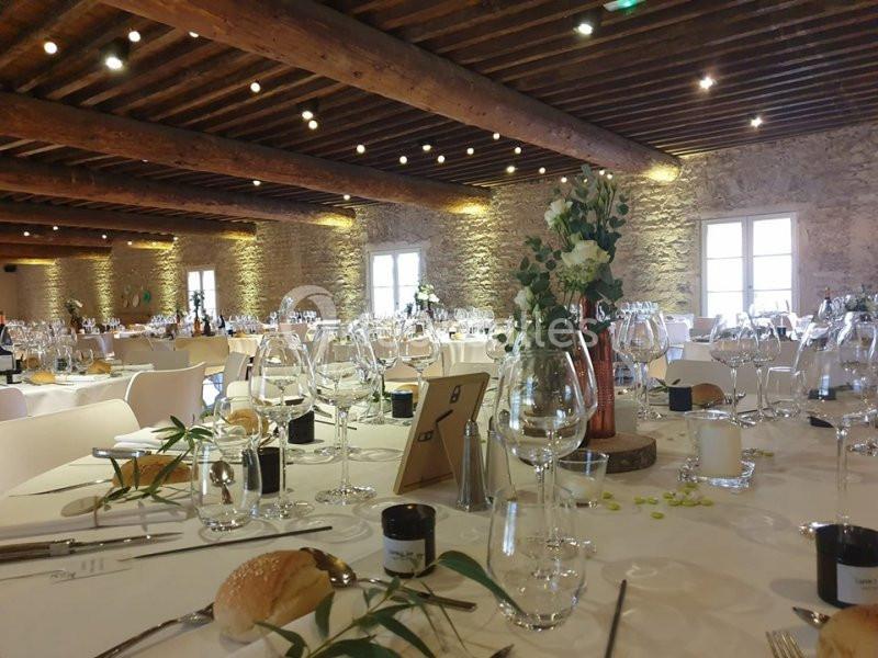 Salle de réception décorée avec des tables dressées, des verres, des fleurs et un éclairage chaleureux.