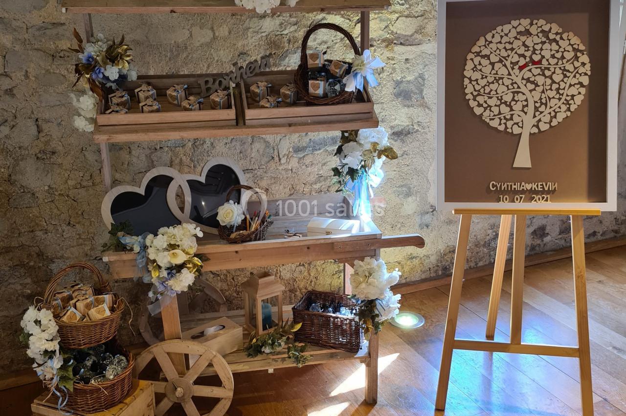 Stand décoratif en bois avec fleurs blanches, accessoires rustiques et tableau d'empreintes en forme d'arbre.