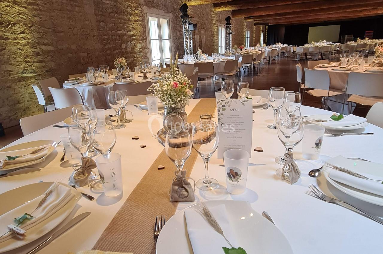 Table élégamment dressée pour un repas, avec nappes blanches, chemins de table en toile de jute et décoration florale.