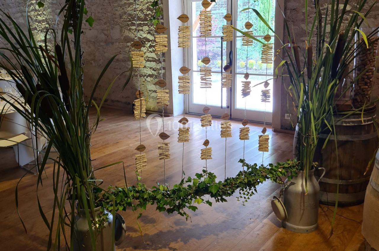 Structure décorative en lierre avec étiquettes suspendues, installée dans une salle en pierre avec parquet et poutres…