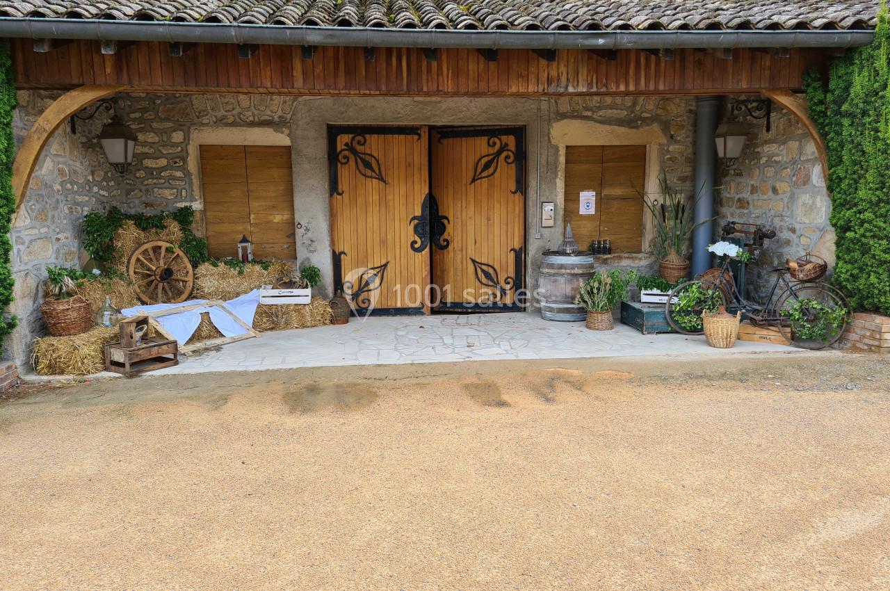 Entrée en bois sculpté d'un bâtiment en pierre, entourée de décorations rustiques avec plantes et objets anciens.