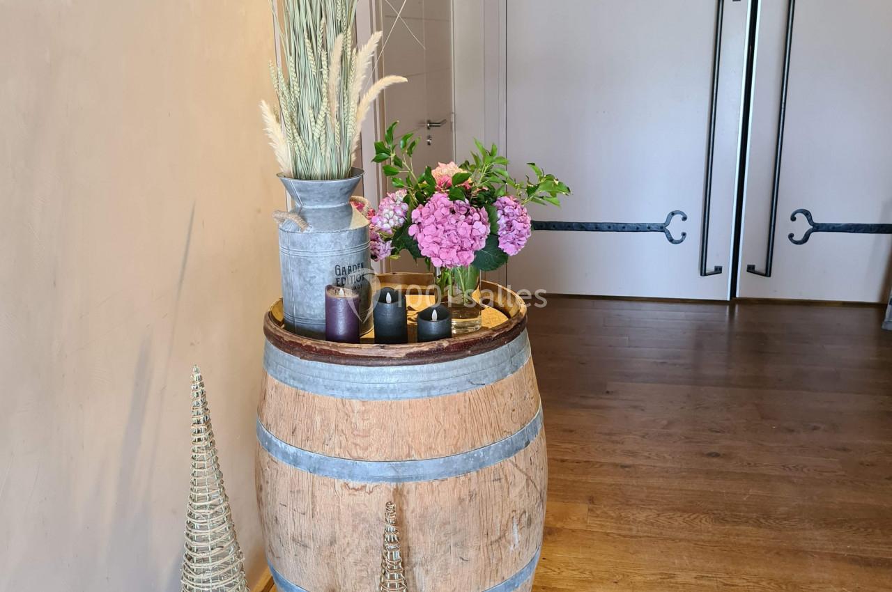 Décoration intérieure avec tonneau en bois, fleurs, bougies et ornements en osier devant des portes doubles.