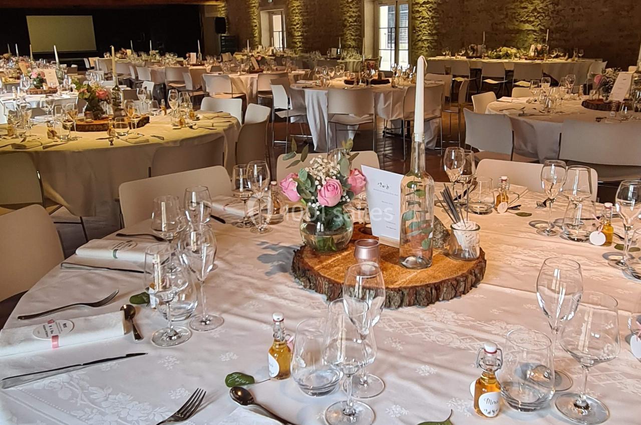 Salle de réception décorée avec des tables rondes élégamment dressées, ornées de centres de table floraux.