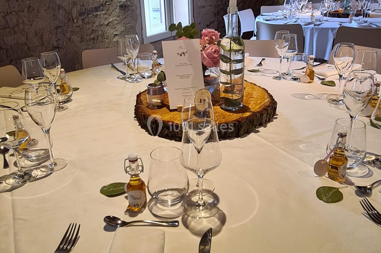 Table de réception décorée avec des éléments rustiques, bougie, menus, et petits flacons en guise de cadeaux invités.