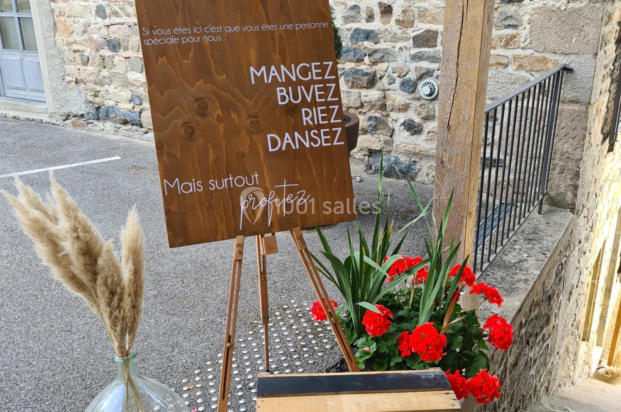 Panneau en bois avec un message festif, entouré de fleurs rouges, d'herbes séchées et d'une caisse décorative.