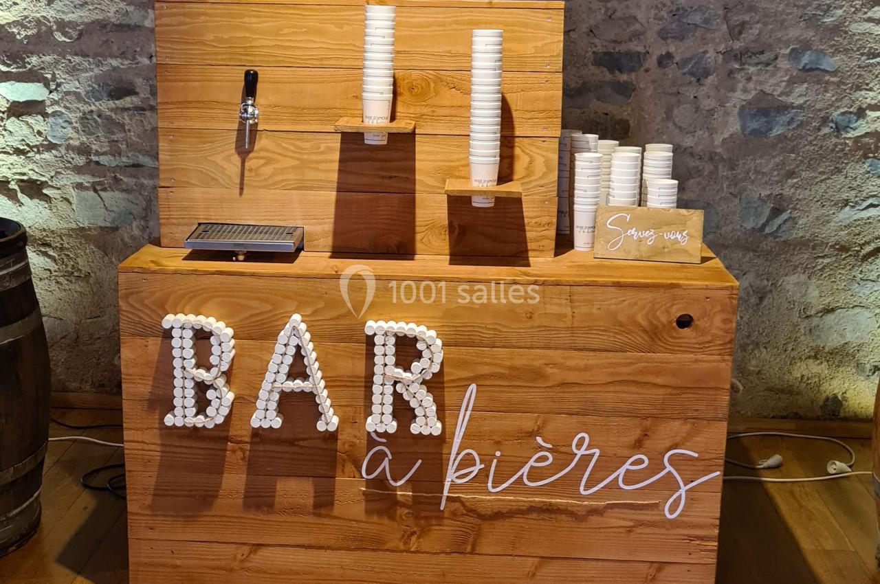 Comptoir en bois avec une inscription ’Bar à bières’, des gobelets empilés et un robinet de distribution.
