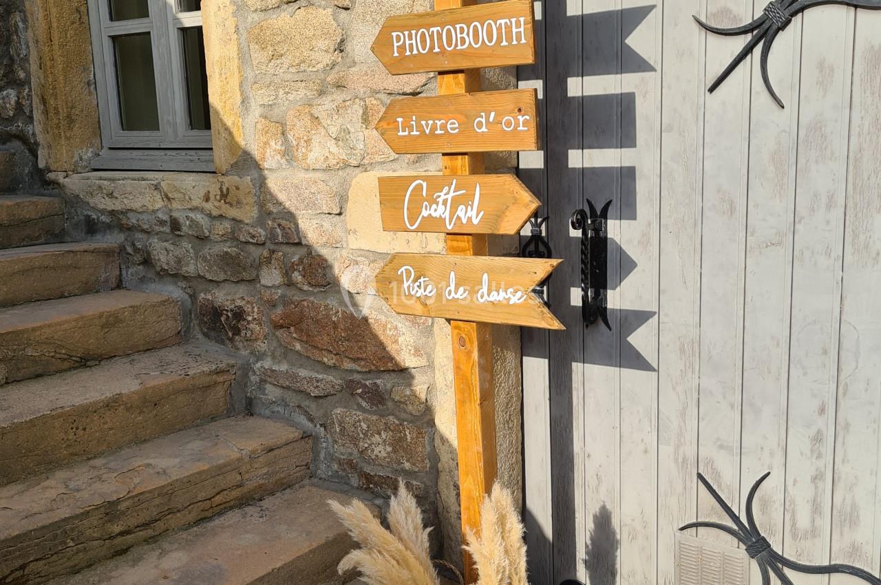 Panneau en bois indiquant des directions pour repas, bar, photobooth, livre d'or, cocktail et piste de danse.