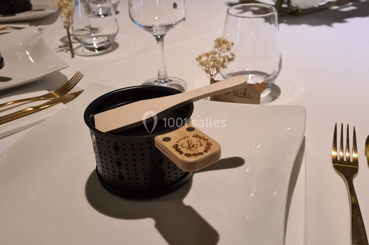 Service de table élégant avec assiette carrée, couverts dorés, verrerie et décoration florale raffinée.
