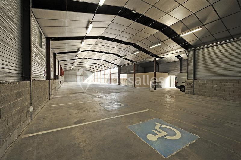 Intérieur d'un entrepôt vide avec des places de stationnement réservées aux personnes handicapées au premier plan.