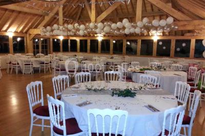 Miniature Location salle Villeneuve-le-Comte (Seine-et-Marne) - Le Domaine de La Pointe #4 Salle de réception décorée avec des guirlandes lumineuses, des tables rondes dressées et un plafond en bois apparent.