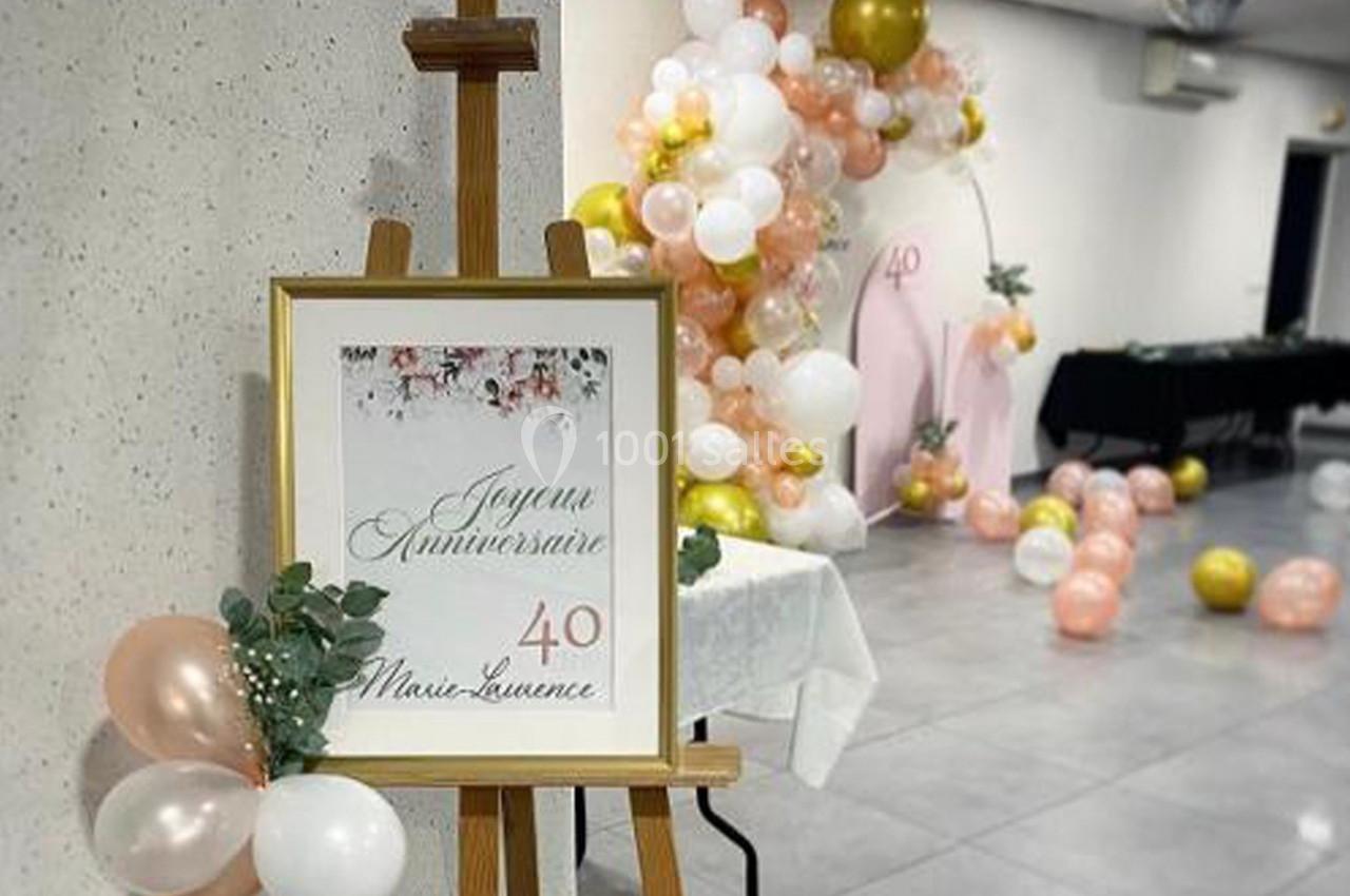 Panneau ’Joyeux Anniversaire 40 Marie-Laurence’ sur un chevalet, décoré de ballons roses, blancs et dorés en arrière-plan.
