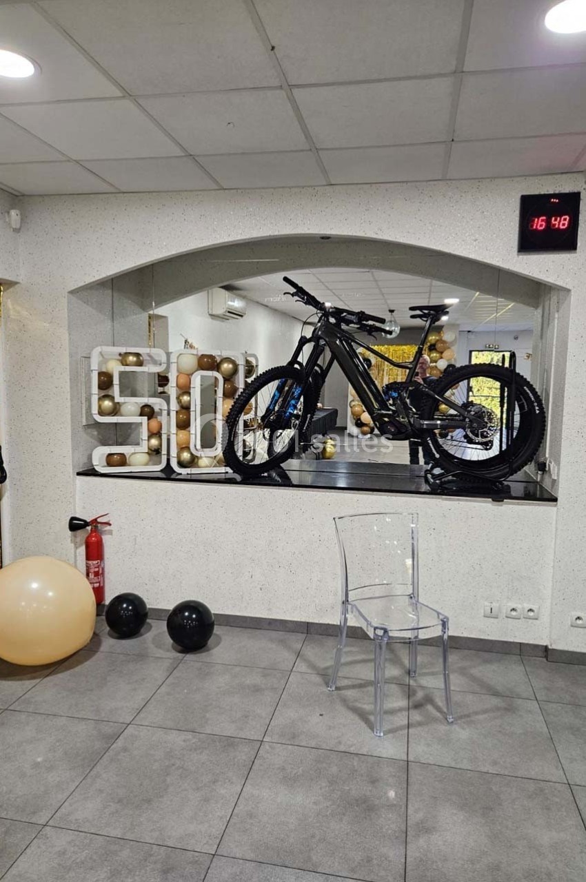 Vélo exposé sur un comptoir devant une décoration avec le chiffre 50, ballons et éléments festifs en arrière-plan.