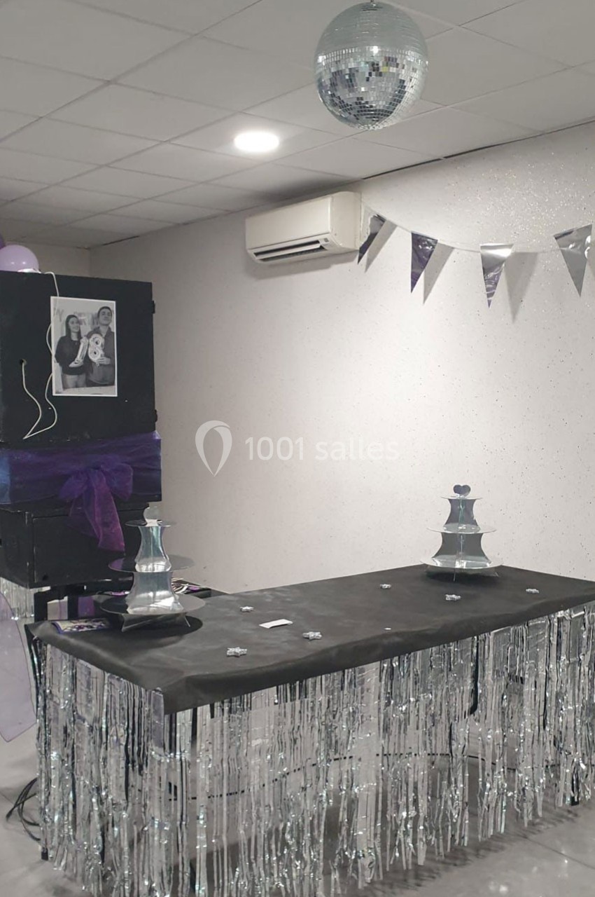 Table décorée avec des guirlandes argentées, une boule disco suspendue et un panneau avec une photo en noir et blanc.