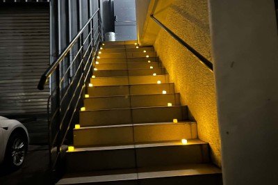 Escalier extérieur éclairé par des bougies LED alignées sur les marches, dans un environnement urbain sombre.