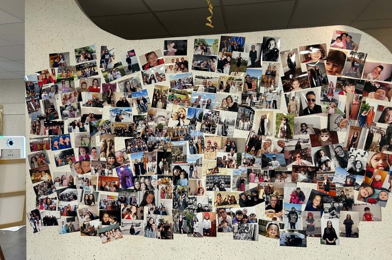 Mur recouvert de nombreuses photos de personnes et de moments variés, affichées dans un espace intérieur.