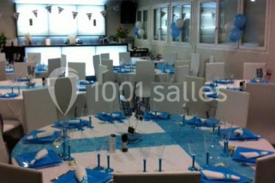 Cuisine professionnelle équipée avec plans de travail en inox, évier double, étagères murales et hotte d'extraction.