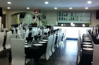 Cuisine professionnelle équipée avec plans de travail en inox, évier double, étagères murales et hotte d'extraction.