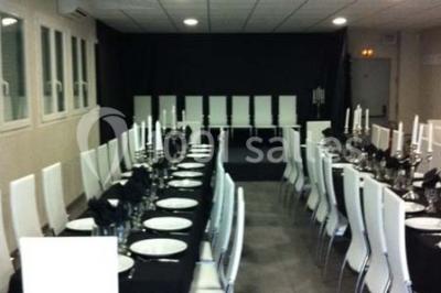 Cuisine professionnelle équipée avec plans de travail en inox, évier double, étagères murales et hotte d'extraction.